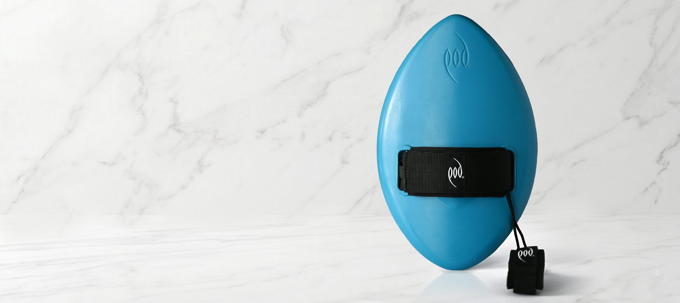 A bright blue handboard with a black strap and leash attached, standing upright on a white marble surface against a white marble background.