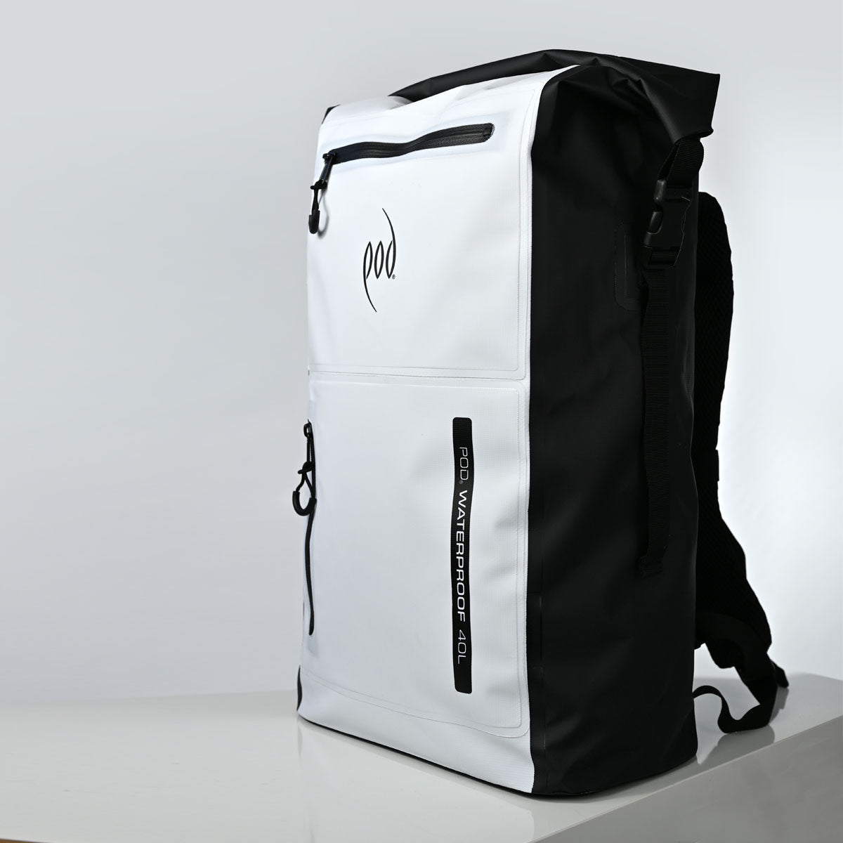 A white and black waterproof backpack with a roll-top closure, shown standing upright on a white surface against a light grey background. The front features a black 'pod' logo and a vertical black label reading 'POD WATERPROOF 40L'.