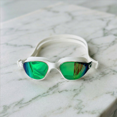 POD AquaLuxe swim goggles with green mirror lenses and white frame resting on a marble surface