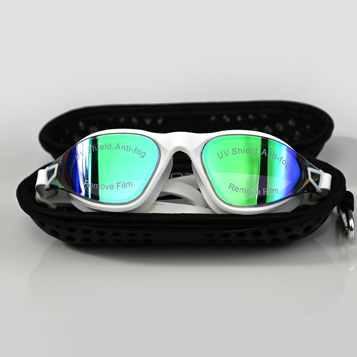 White swim goggles with green-tinted reflective lenses, displayed inside an open black zippered case on a light gray background.