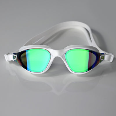 White swimming goggles with large mirrored green lenses, shown on a clean light gray reflective surface.